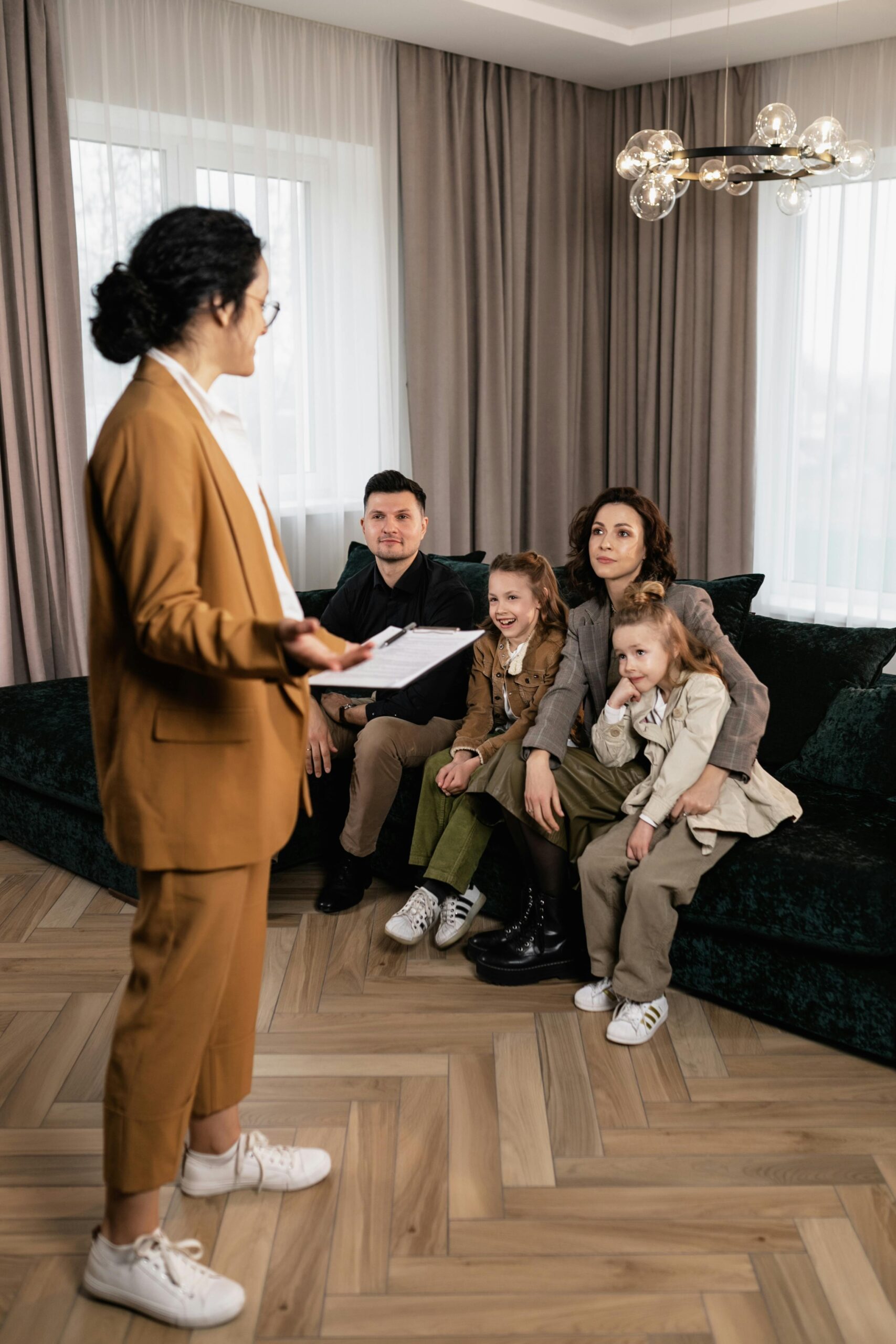 A family sits on a couch while talking to a real estate agent about buying a house.