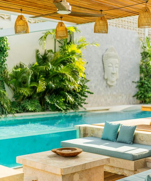 Elegant outdoor pool area featuring tropical plants and modern seating for relaxation.